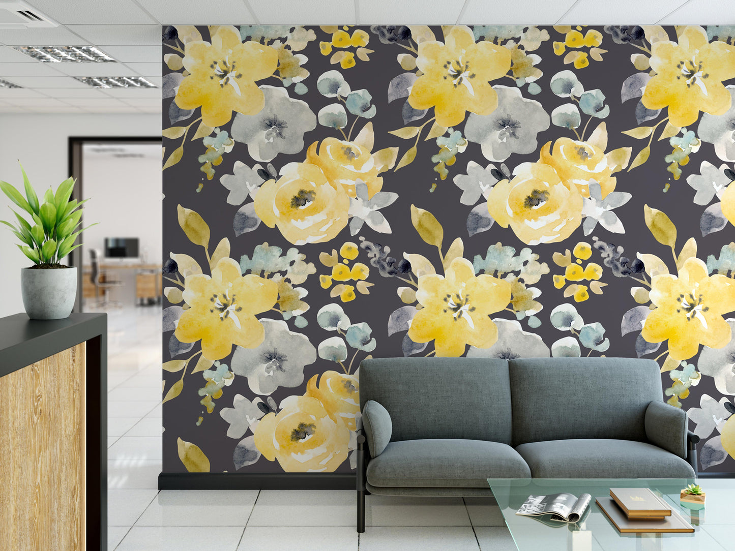 a modern office space with a large wall mural depicting a floral pattern in shades of yellow and gray. In the foreground, there is a gray sofa and a glass coffee table.