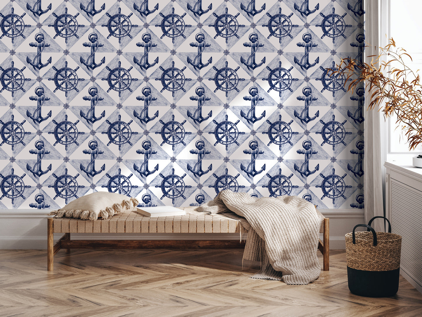 a room with a large wallpapered wall adorned with a repeating pattern of blue anchors and ship wheels. In the foreground, there is a wooden bench with a blanket draped over it, and a woven basket next to it.