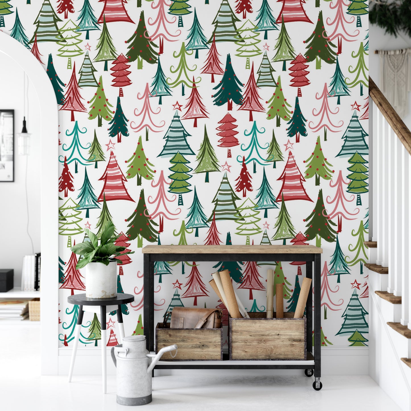 a festive wall with a pattern of colorful Christmas trees in various shades of green, red, and white. In front of the wall, there is a small table with a plant and a metal crate, and a staircase can be seen in the background.