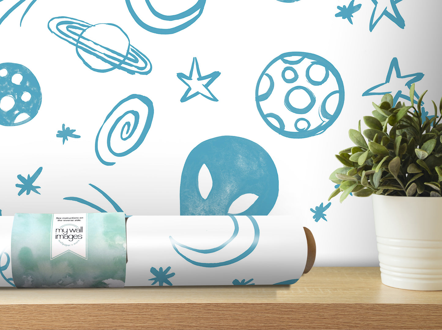 a wall with a blue and white space-themed wallpaper, along with a potted plant and a roll of wallpaper on a shelf.