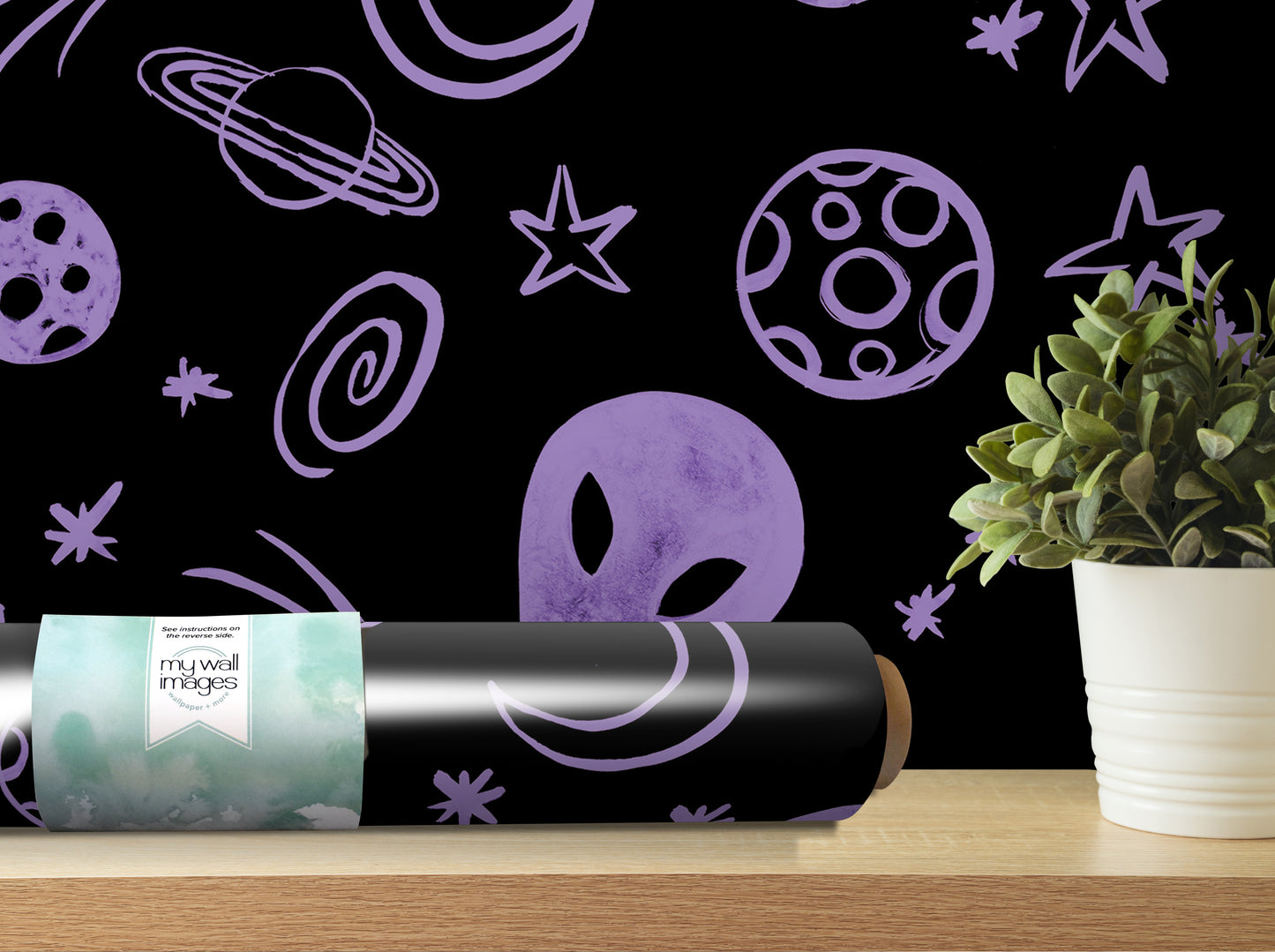 a black roller with a purple alien face design on it, placed on a wooden shelf next to a potted plant.