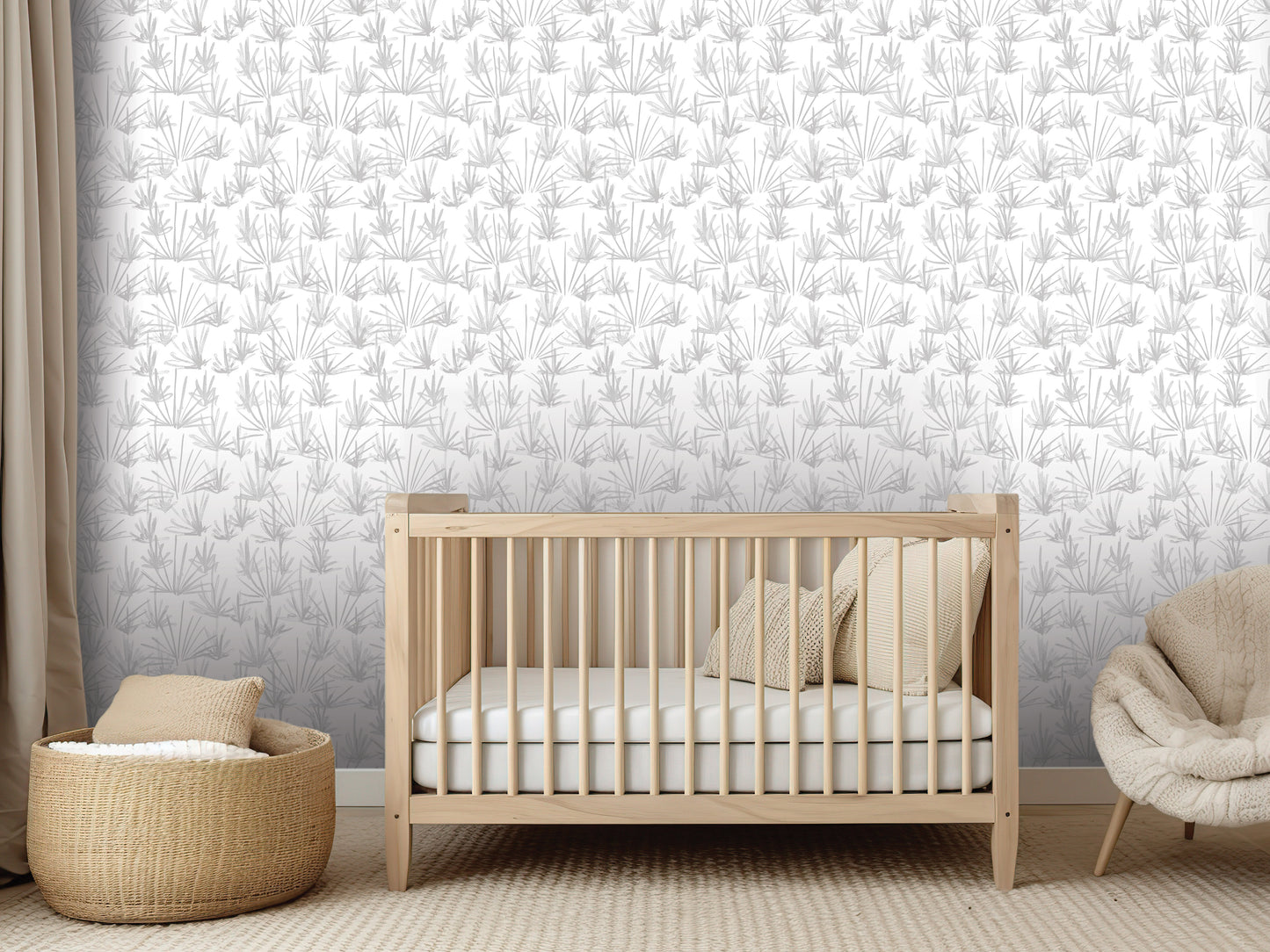 a modern nursery with a wooden crib, a woven basket, and a beige chair. The crib is positioned against a wall with a repeating pattern of gray and white leaves.