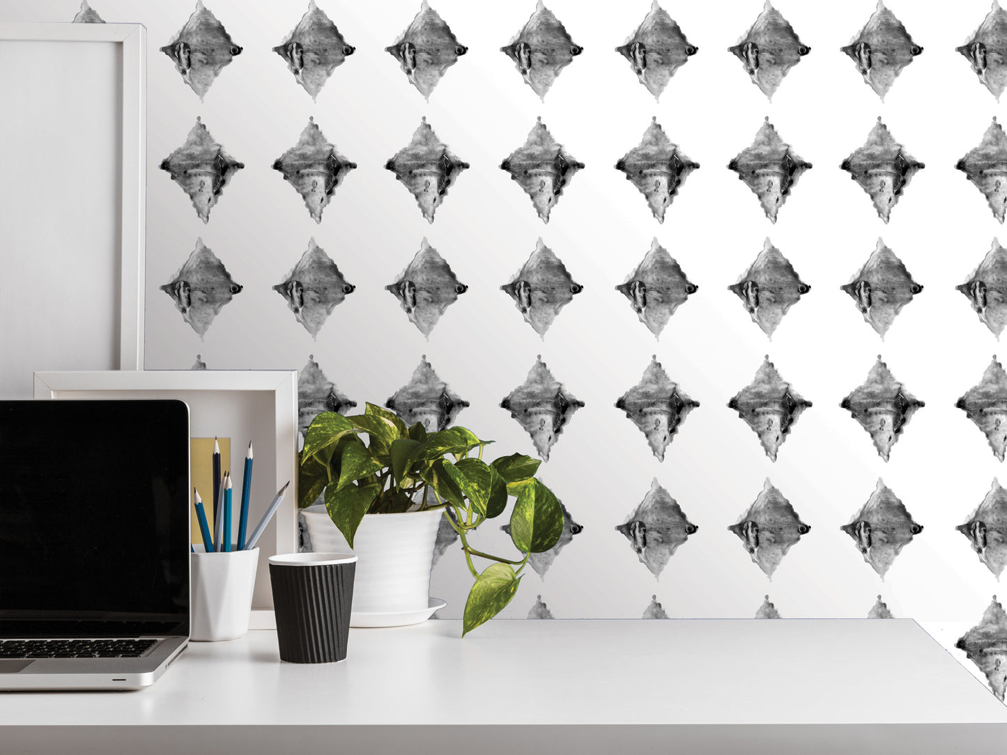 a white desk with various items on it, including a laptop, a plant, and a cup. The background has a repeating pattern of black and white diamond shapes.