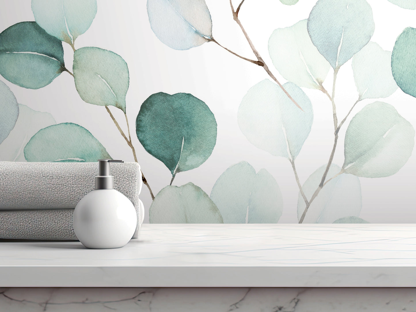 a white countertop with a white soap dispenser and a folded towel, set against a wall with a watercolor-style wallpaper pattern of green leaves.