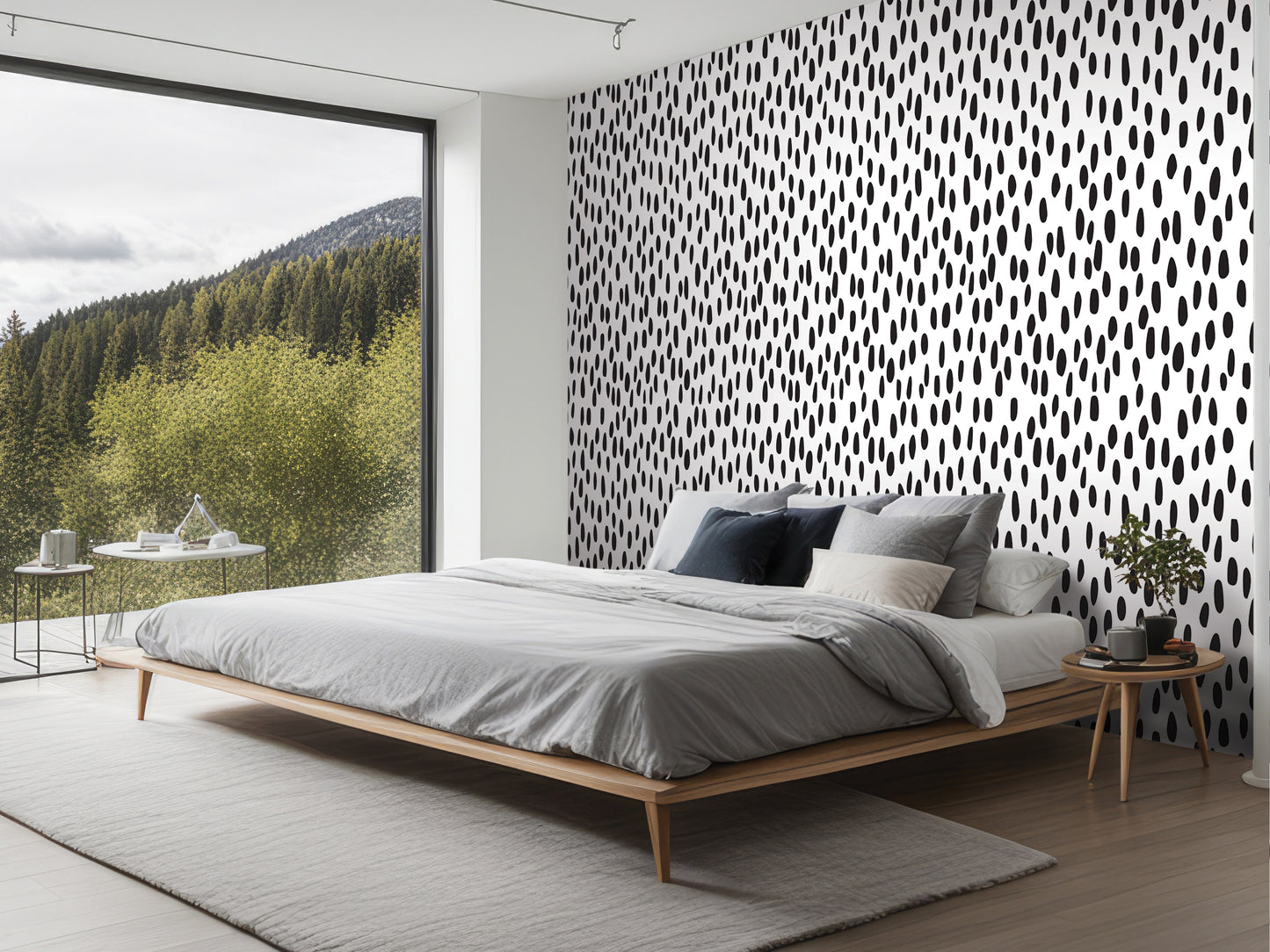 a modern bedroom with a large bed, a nightstand, and a window overlooking a forested area.
