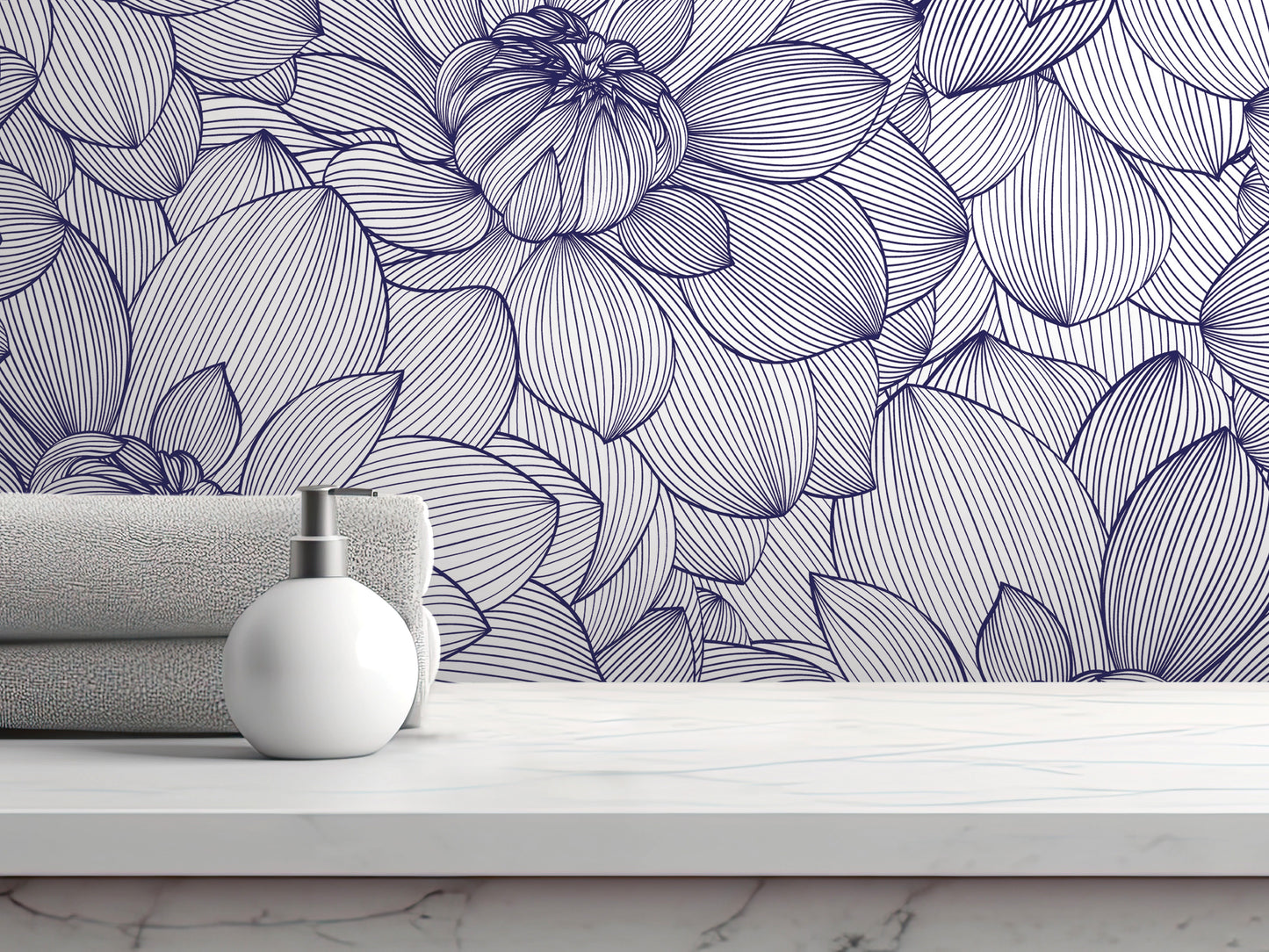 a white soap dispenser on a white marble countertop, with a folded towel and a white bottle of lotion placed next to it. The background is a wall with a floral pattern in shades of blue and white.