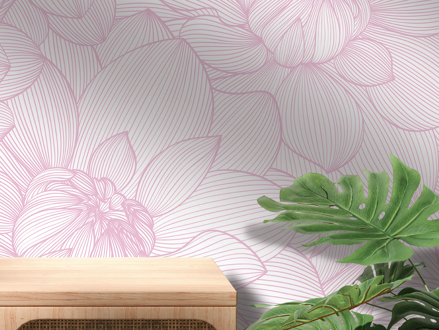a pink floral pattern on the wall behind a wooden table, with a large green leaf plant in the foreground.