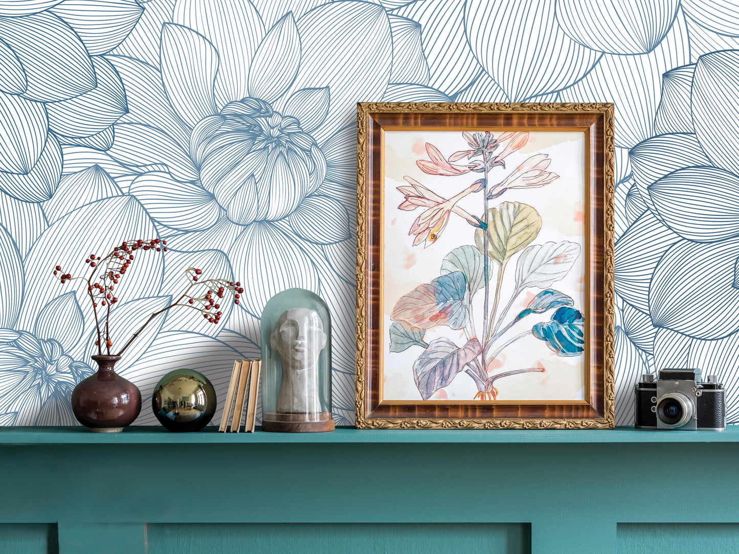 a shelf with various decorative items, including a framed floral artwork, a vase with flowers, a glass dome, a camera, and a few books. The shelf has a teal color and is set against a blue and white floral wallpaper.