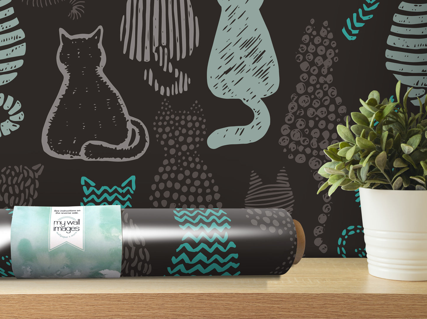 a black and teal cat wallpaper roll placed on a wooden shelf next to a potted plant.