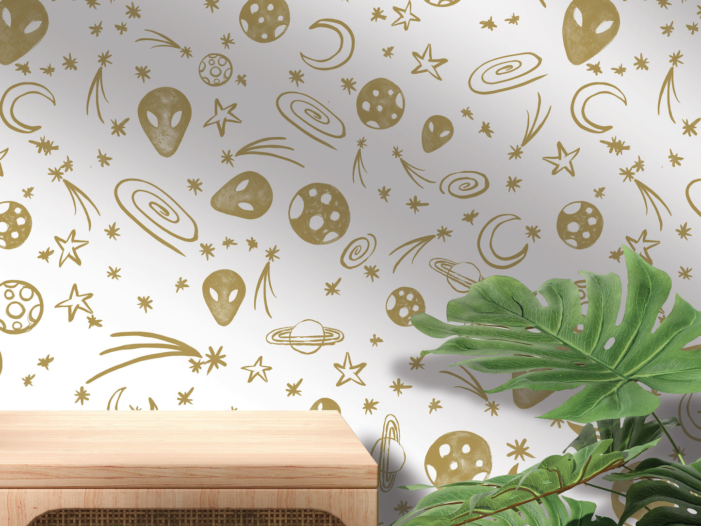 a wall with a pattern of gold stars, planets, and other celestial objects, along with a wooden shelf or table in the foreground.