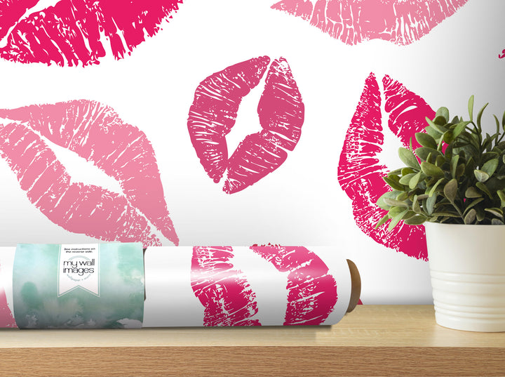 a wall with a large pink kiss print design, including multiple lips and a plant in a white pot.