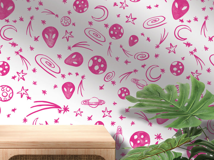 a wall with a vibrant, space-themed wallpaper adorned with various celestial objects such as planets, stars, and comets. The wall also has a wooden shelf or table in the foreground, adding a natural element to the scene.