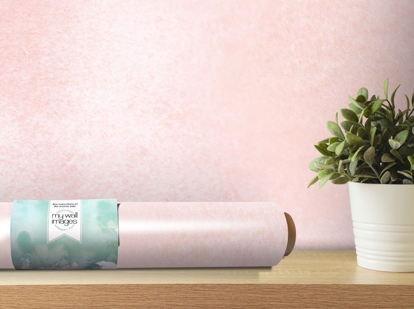 a roll of wallpaper with a label, a potted plant, and a wooden shelf against a pink textured wall.