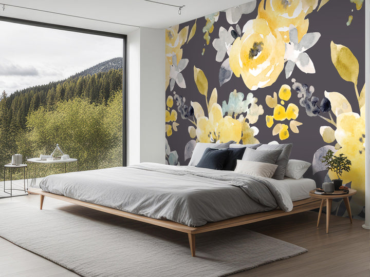 a modern bedroom with a large floral mural on the wall behind the bed. The mural features a variety of yellow and green flowers, creating a vibrant and lively atmosphere in the room. The bed is positioned in the center of the room, with a wooden headboard and footboard. The room also includes a nightstand and a small table, adding to the overall aesthetic and functionality of the space.