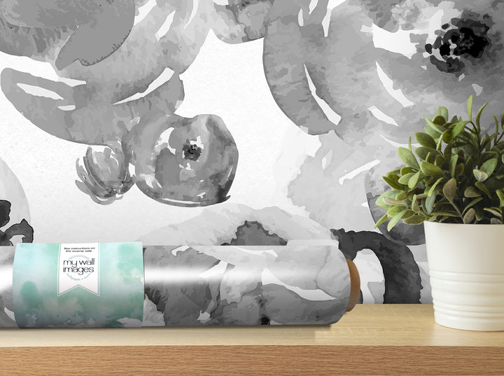 a large abstract floral pattern on a wall, with a potted plant and a roll of wallpaper or wall covering in the foreground.