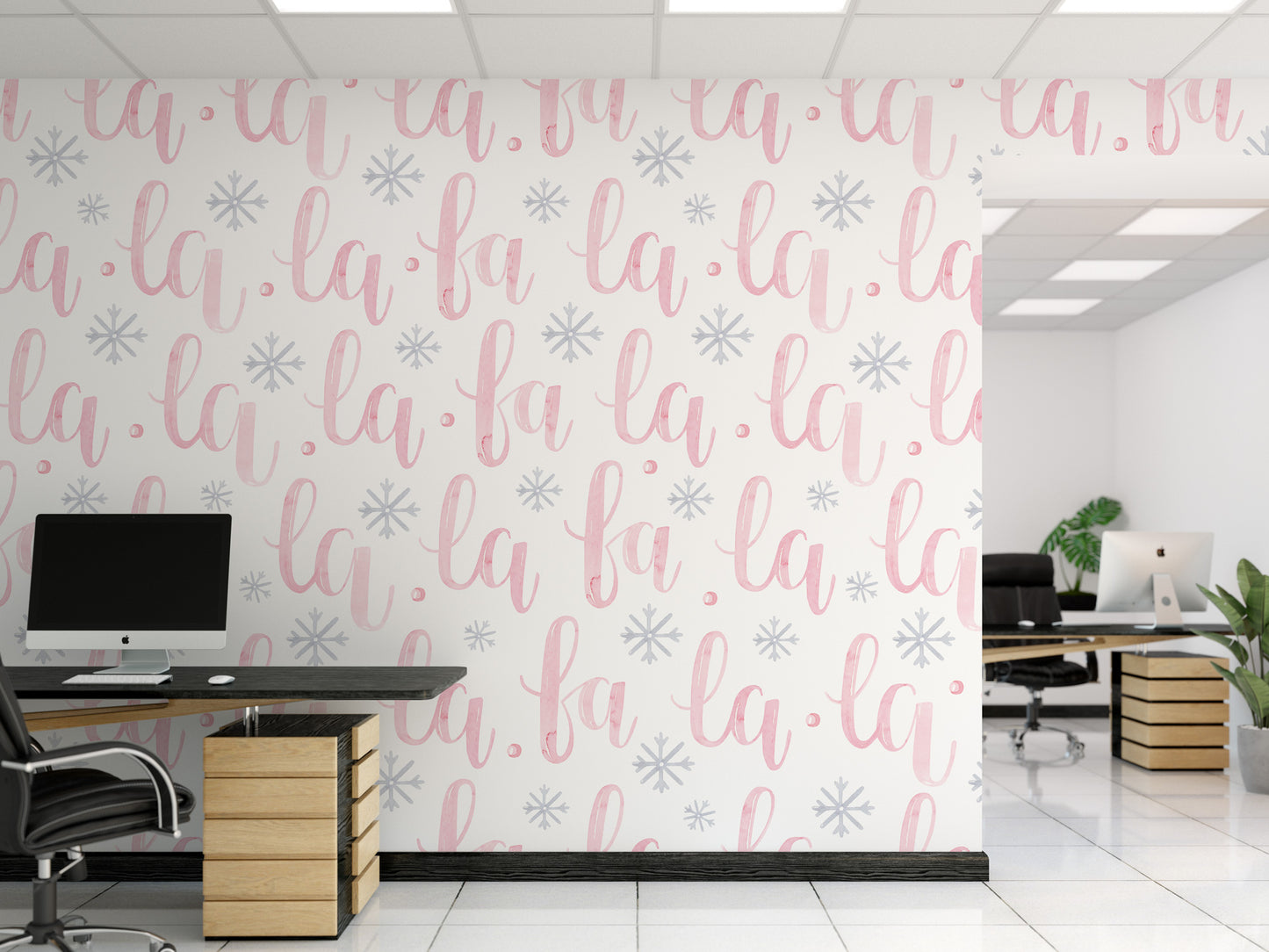 a modern office space with a wall adorned with a repeating pattern of the word "la" in pink and white cursive font, along with snowflake designs. The office has a black desk with a computer monitor, a potted plant, and a chair.