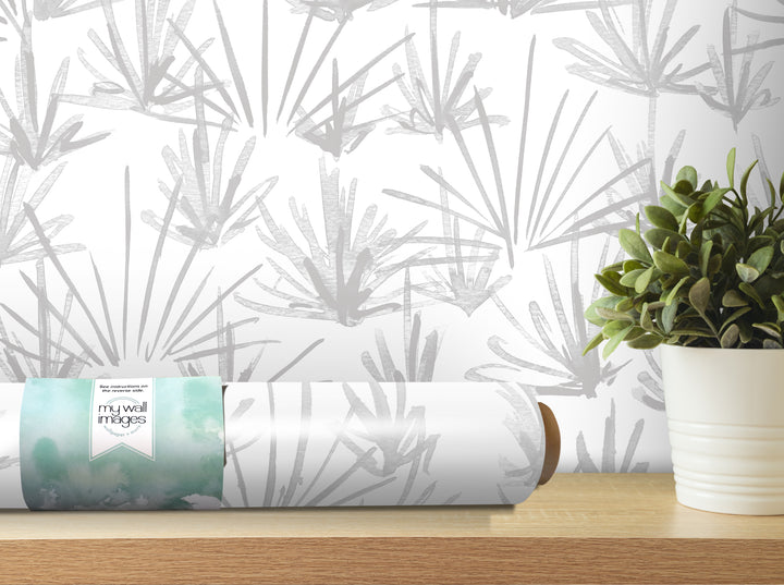 a roll of wallpaper with a gray and white abstract pattern, placed on a wooden shelf next to a potted plant.