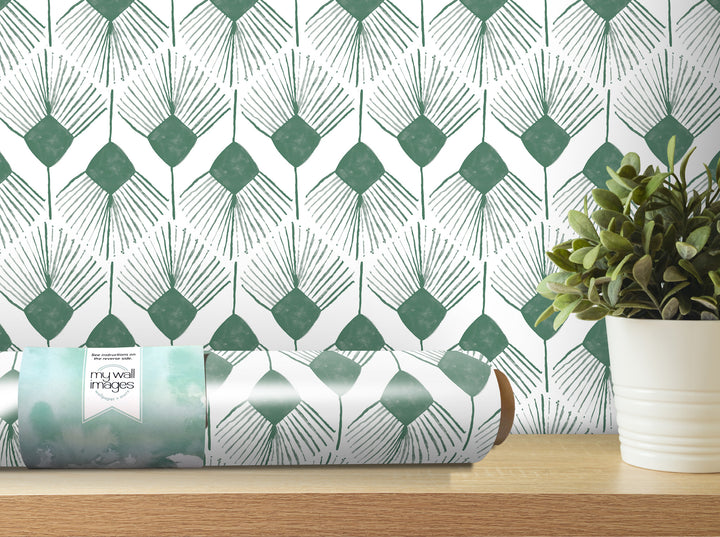 a roll of wallpaper with a repeating pattern of green and white diamond shapes, placed on a wooden shelf next to a potted plant.