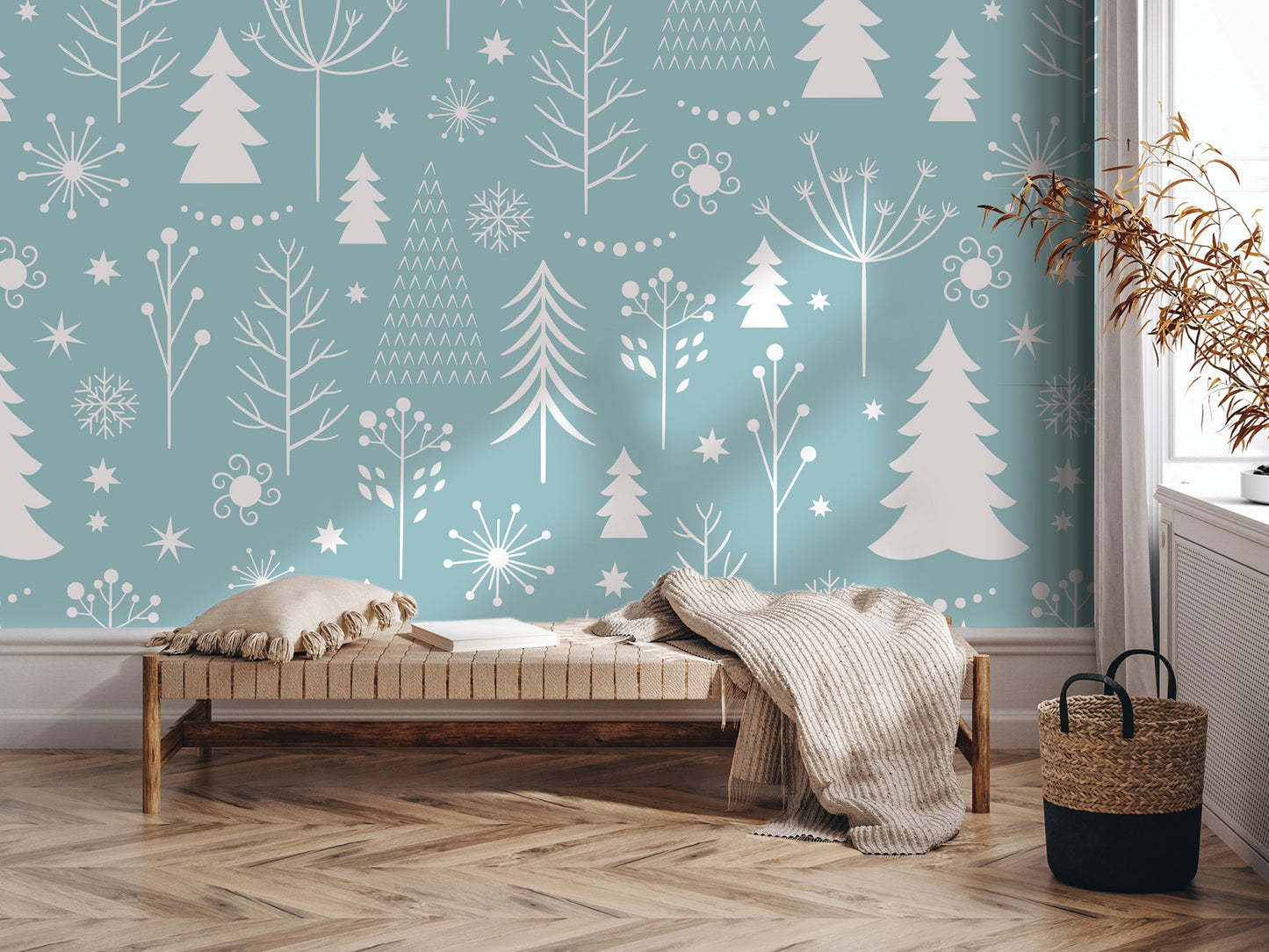 a cozy and inviting living space with a wooden floor and a comfortable bench. The wall behind the bench is decorated with a pattern of white trees and snowflakes, creating a wintery atmosphere. A woven basket is placed next to the bench, and a potted plant is located nearby. The overall scene conveys a sense of warmth and tranquility, with the natural elements complementing the comfortable furnishings.