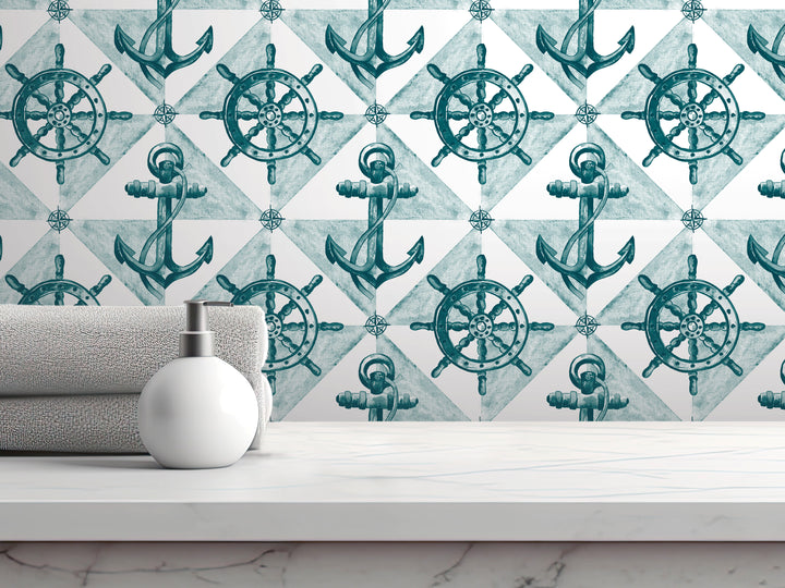 a bathroom setting with a white countertop, a white soap dispenser, and a towel. Behind the countertop, there is a wall with a repeating pattern of anchors and ship's wheels, creating a nautical theme.