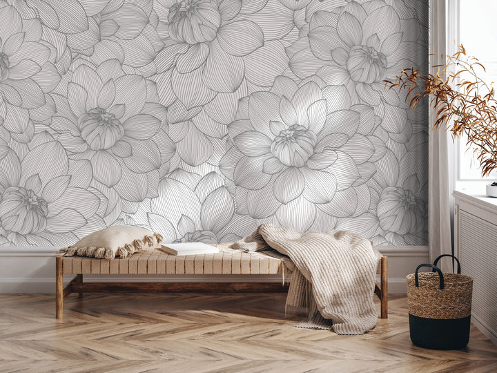 a modern and minimalist interior design with a large wallpapered wall featuring a repeating pattern of large white flowers. In the foreground, there is a wooden bench with a beige blanket draped over it, and a woven basket next to it. The overall color scheme is neutral, with the white flowers and beige tones creating a harmonious and visually appealing space.