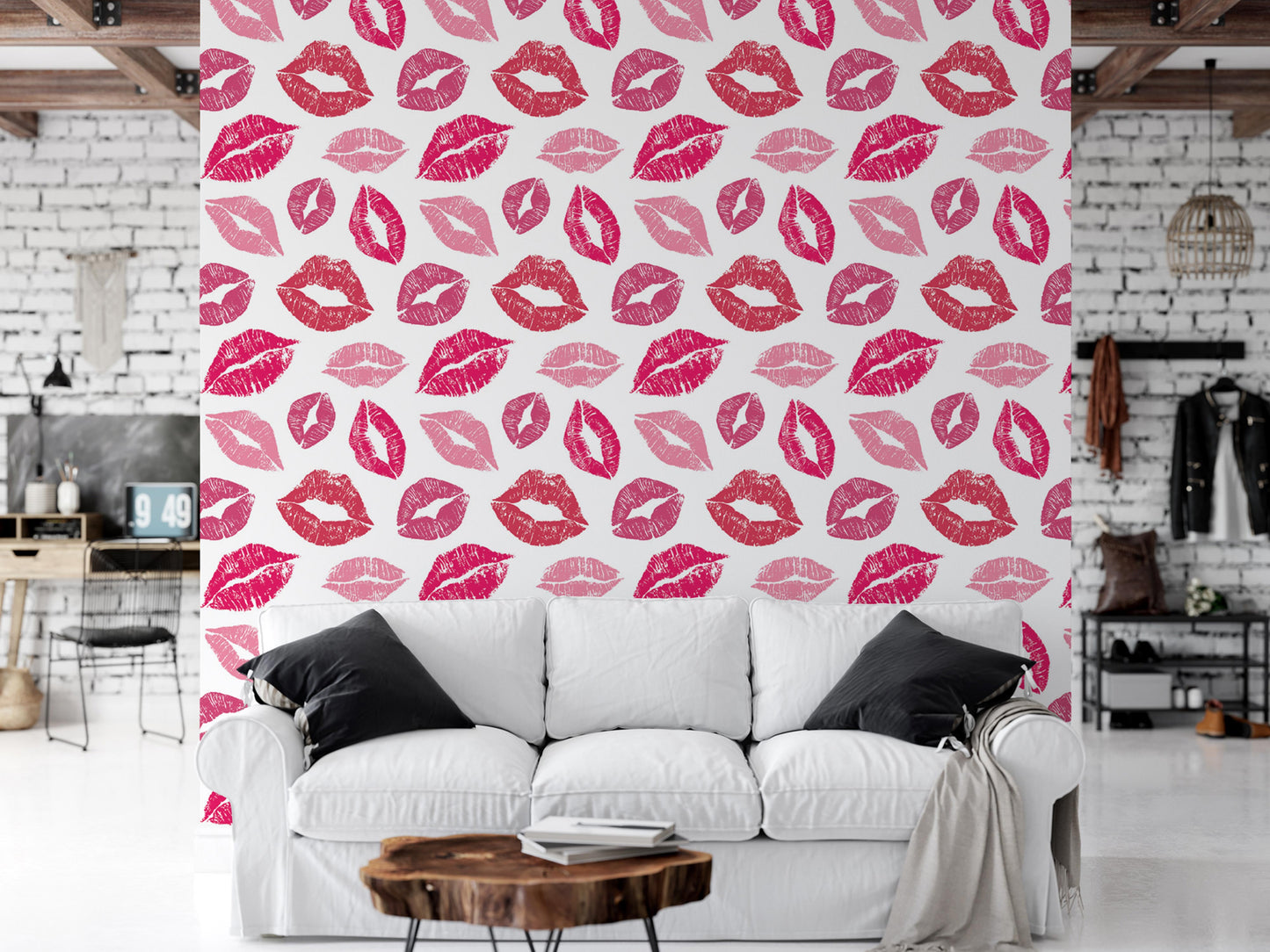 a white couch with black pillows, positioned in front of a wall with a repeating pattern of pink and red lips on a white background.
