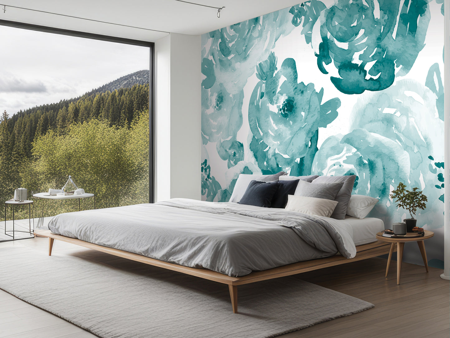 a modern bedroom with a large window overlooking a forested area. The room features a wooden bed frame, a gray comforter, and a wooden nightstand with a plant. The walls are adorned with a large watercolor mural depicting a floral pattern in shades of blue and green.