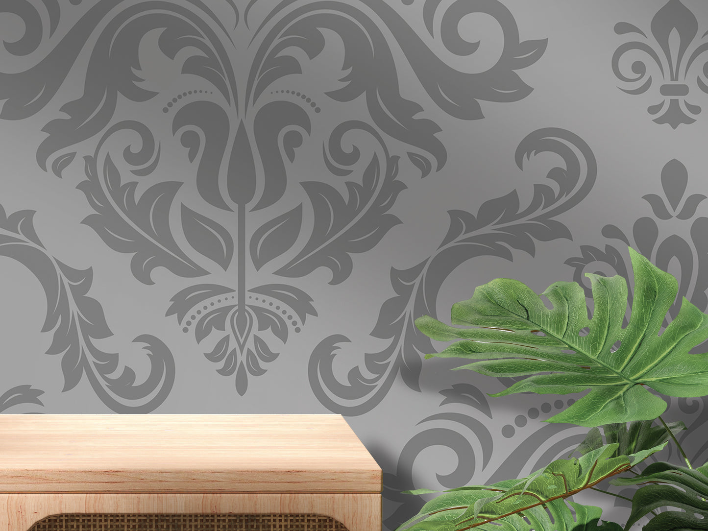 a gray wall with a decorative floral pattern, a wooden table or shelf, and a large green leafy plant.