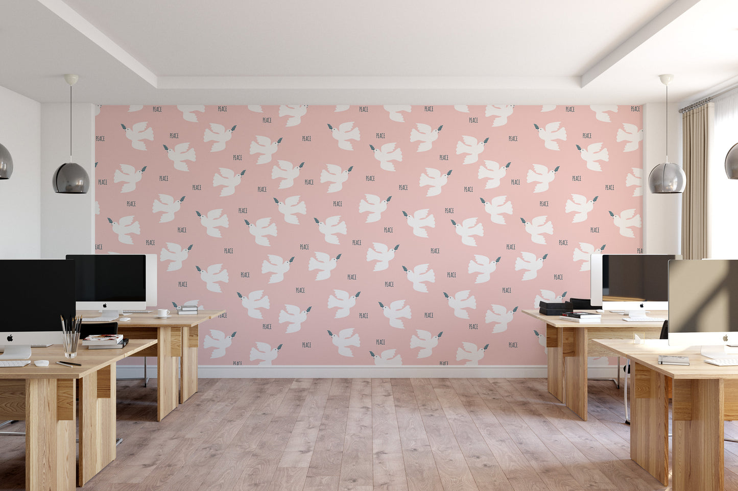 a modern office space with a pink wall featuring a repeating pattern of white birds. The room contains several wooden desks with computer monitors, and the floor is made of wood.