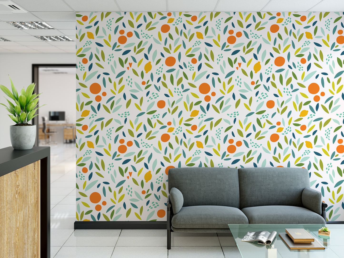 a modern office space with a vibrant wall mural of orange and green leaves, creating a lively and refreshing atmosphere. In the foreground, there is a gray sofa and a glass coffee table, providing a comfortable seating area. The office also includes a reception desk with a potted plant, adding a touch of greenery to the space.