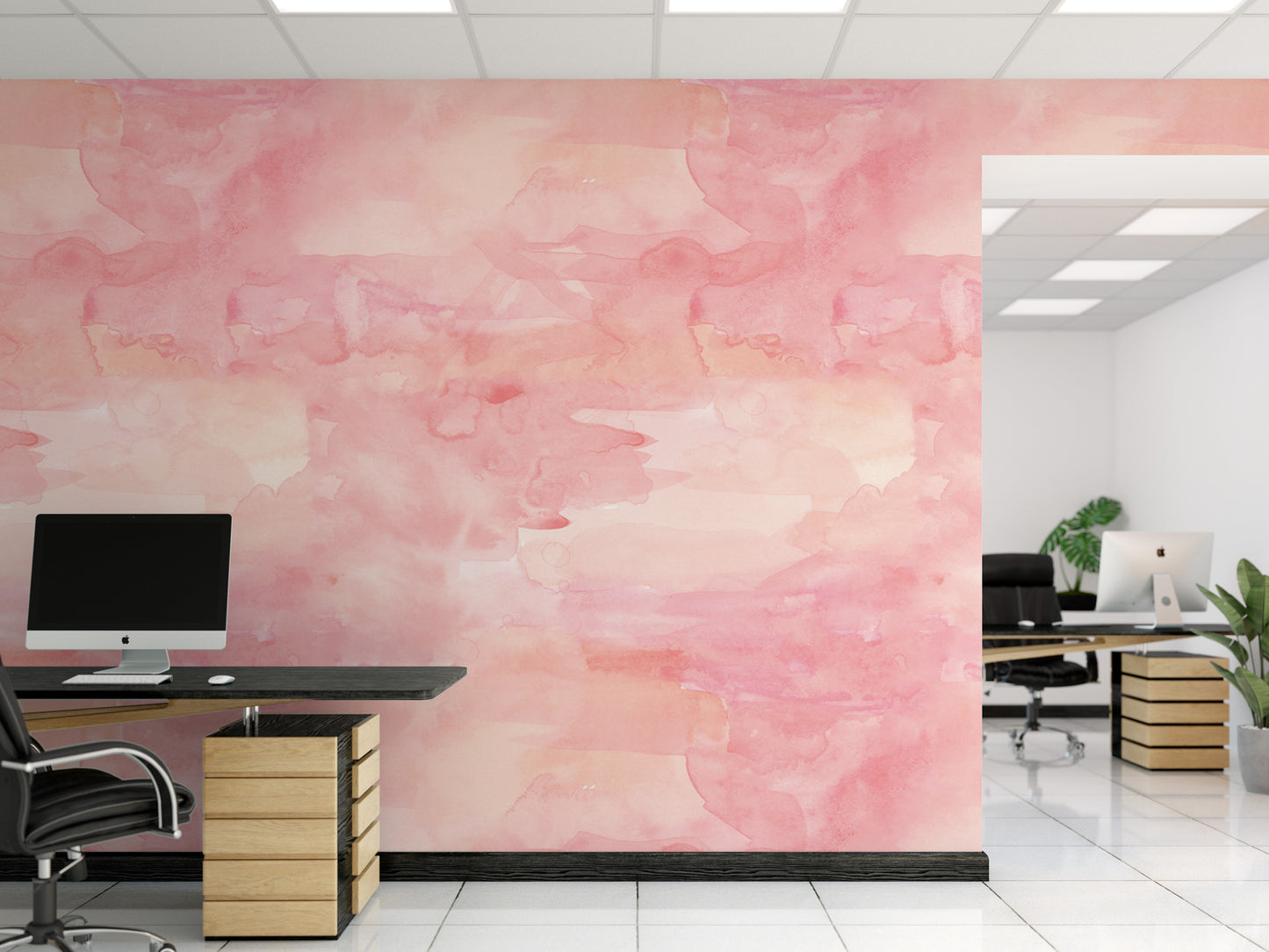 a modern office space with a pink watercolor-style wall behind a desk. The desk has a computer monitor, keyboard, and mouse on it. There are two chairs in the room, one near the desk and another further away. The office appears to be well-lit and organized, with a potted plant adding a touch of greenery to the space.
