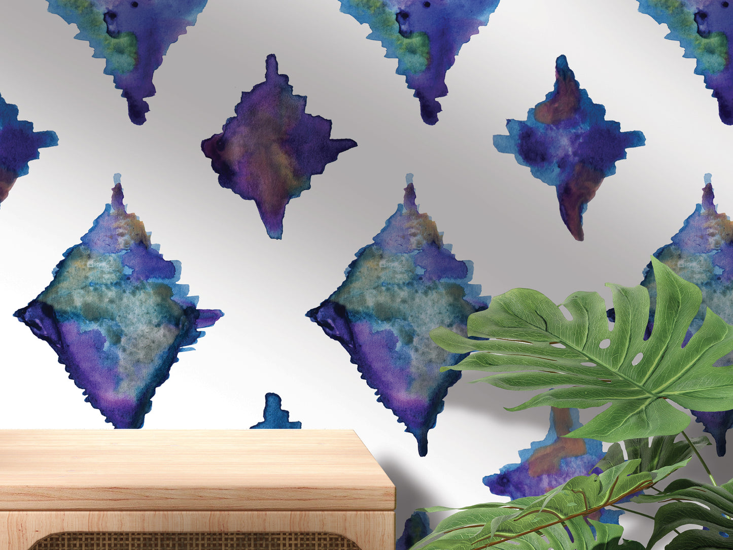 a wall with a repeating pattern of abstract watercolor-style shapes in shades of blue, purple, and green. In the foreground, there is a wooden table and a plant, creating a natural and artistic setting.