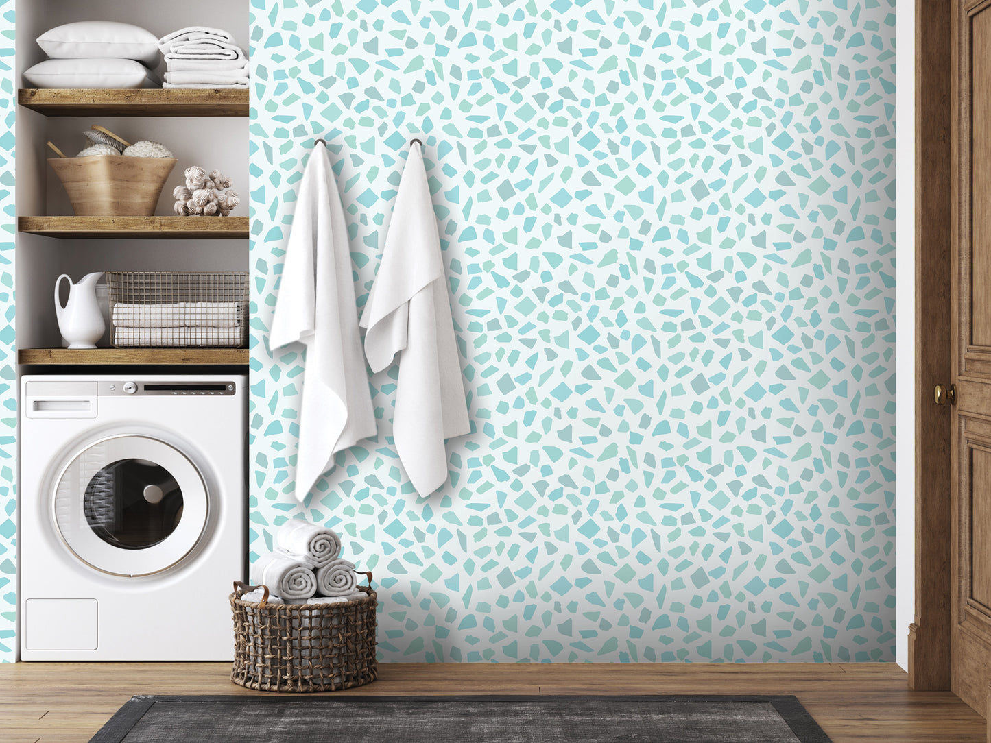 a bathroom with a tiled wall featuring a mosaic pattern in shades of blue and white. The bathroom is equipped with a washing machine and a wooden shelf with various items, including towels and baskets.