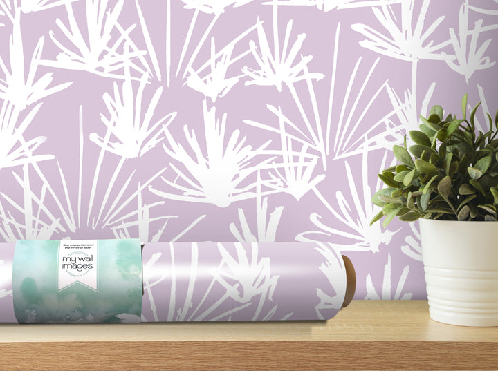 a roll of wallpaper with a white floral pattern on it, placed on a wooden shelf next to a potted plant.