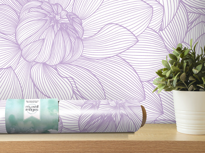 a purple and white floral wallpaper on the wall, with a potted plant and a roll of wallpaper on a shelf in the foreground.