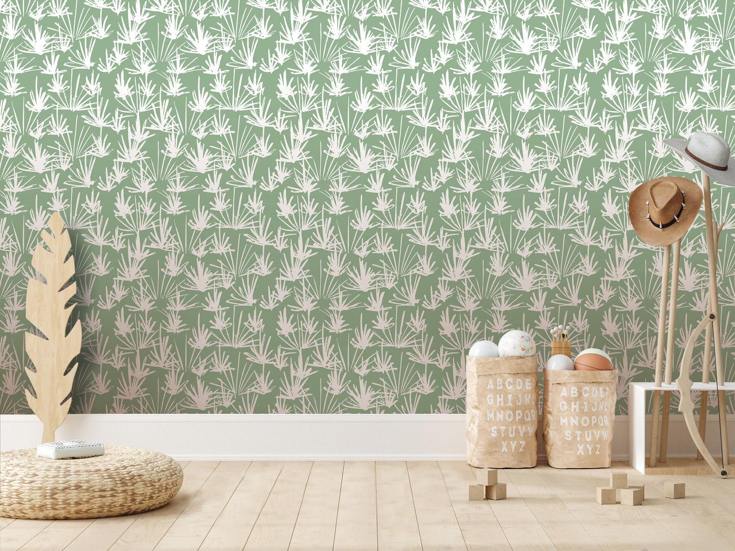 a room with a green wall adorned with a repeating pattern of white palm leaves. The room has a wooden floor and a wicker mat on the floor. There are two wooden stools, a wooden hat rack, and a wooden surfboard leaning against the wall. The room also contains a wooden table with a white lamp and a wooden hat stand.
