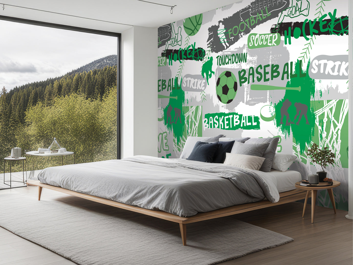 a bedroom with a large wall mural depicting various sports-related words and images, including soccer, basketball, and hockey. The room has a bed, nightstand, and a large window overlooking a forested area.