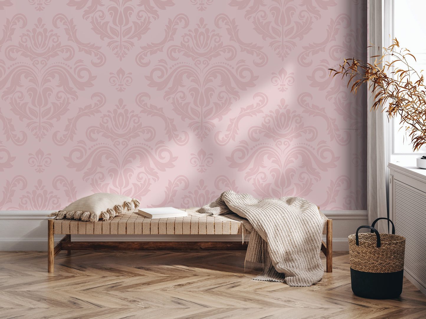 a cozy and inviting living space with a plush bench, a woven basket, and a decorative plant. The bench is adorned with a throw blanket and a pillow, creating a comfortable seating area. The woven basket is placed next to the bench, and the plant adds a touch of nature to the room. The walls are covered in a pink and white patterned wallpaper, which complements the overall aesthetic of the space.