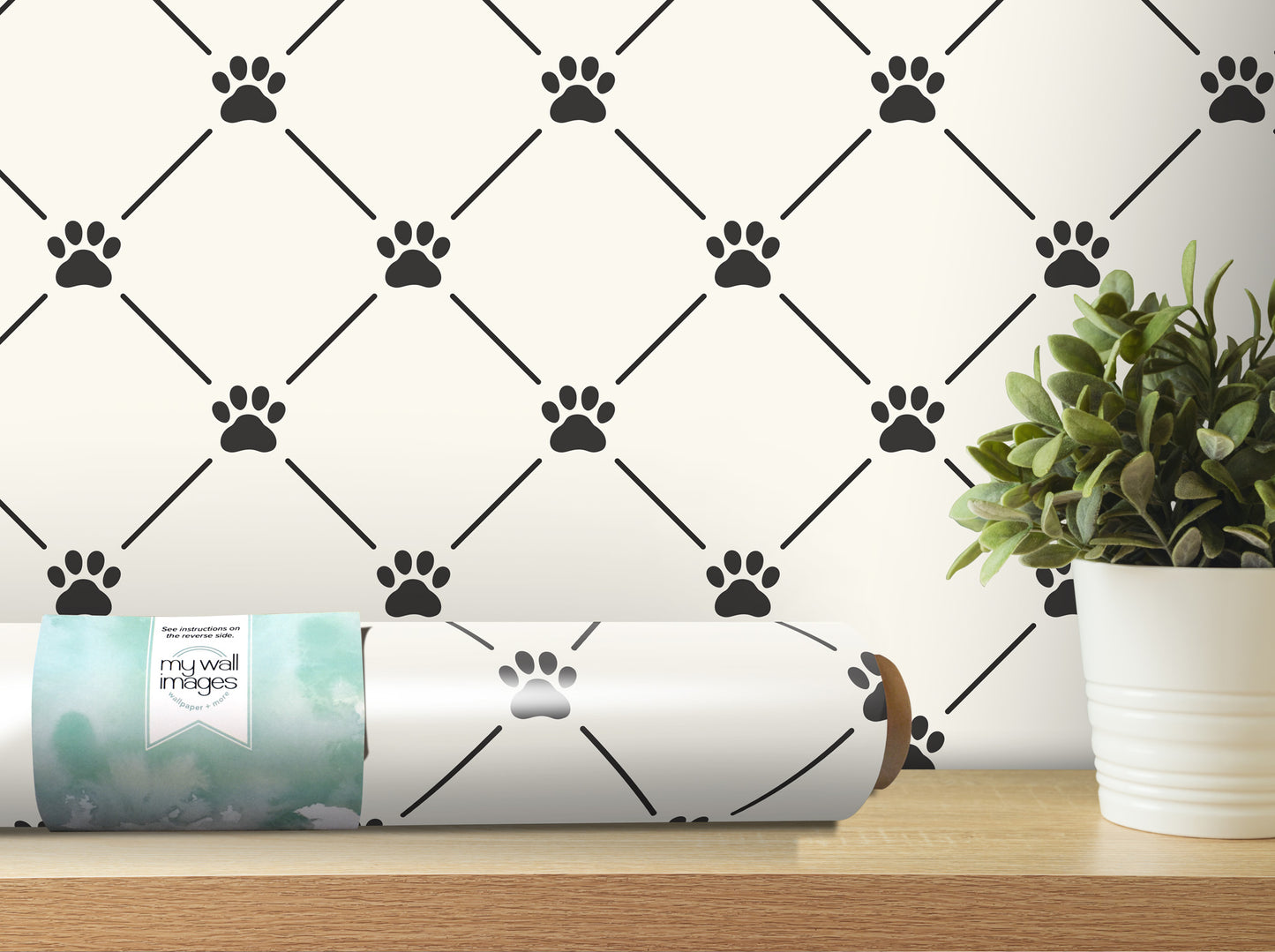 a wall with a repeating pattern of black paw prints, and there is a potted plant and a roll of wallpaper with paw prints on a shelf in the foreground.