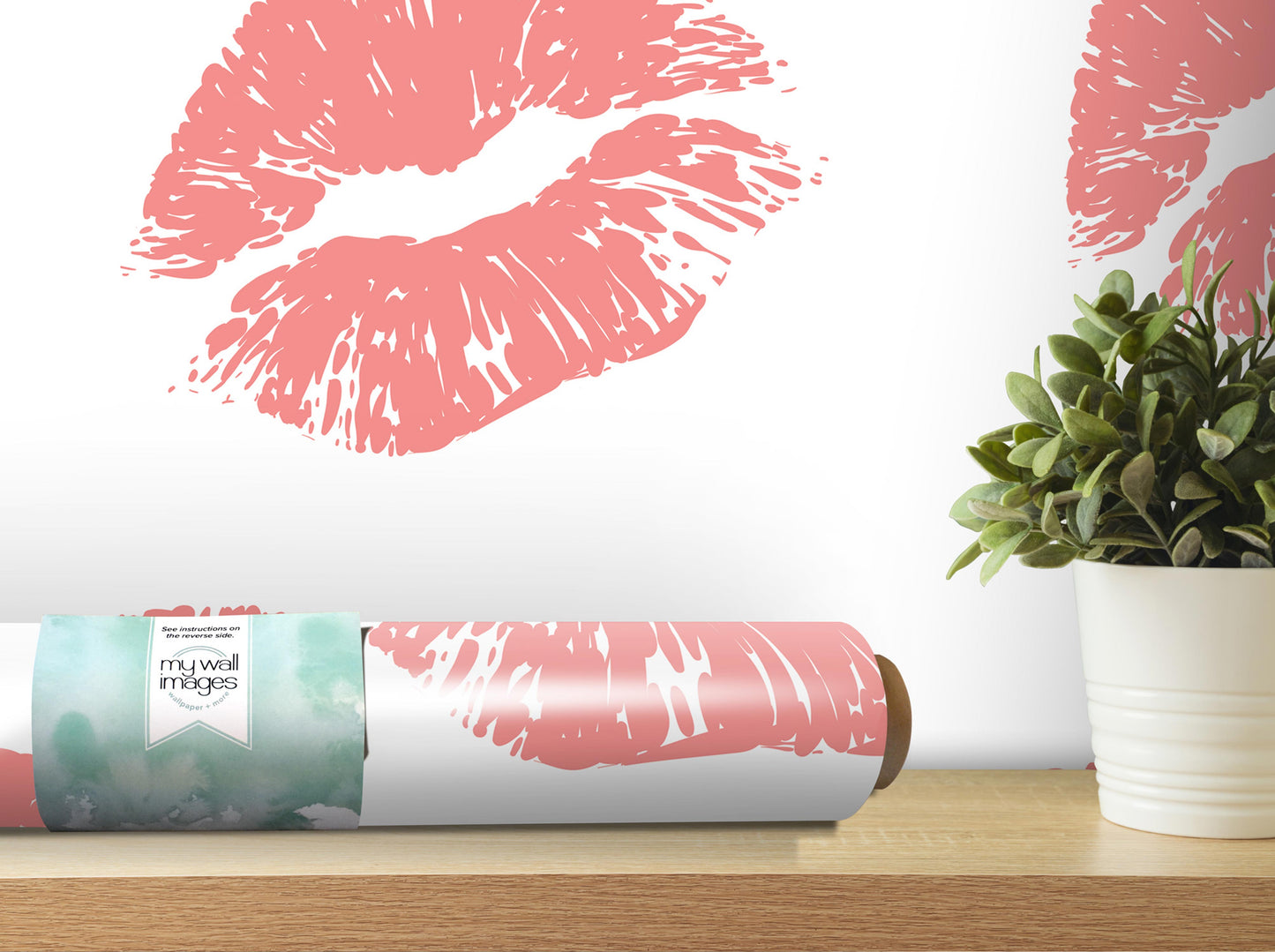 a pink and white wallpaper with a large pink kiss-like design on it, along with a potted plant and a roll of wallpaper on a shelf.