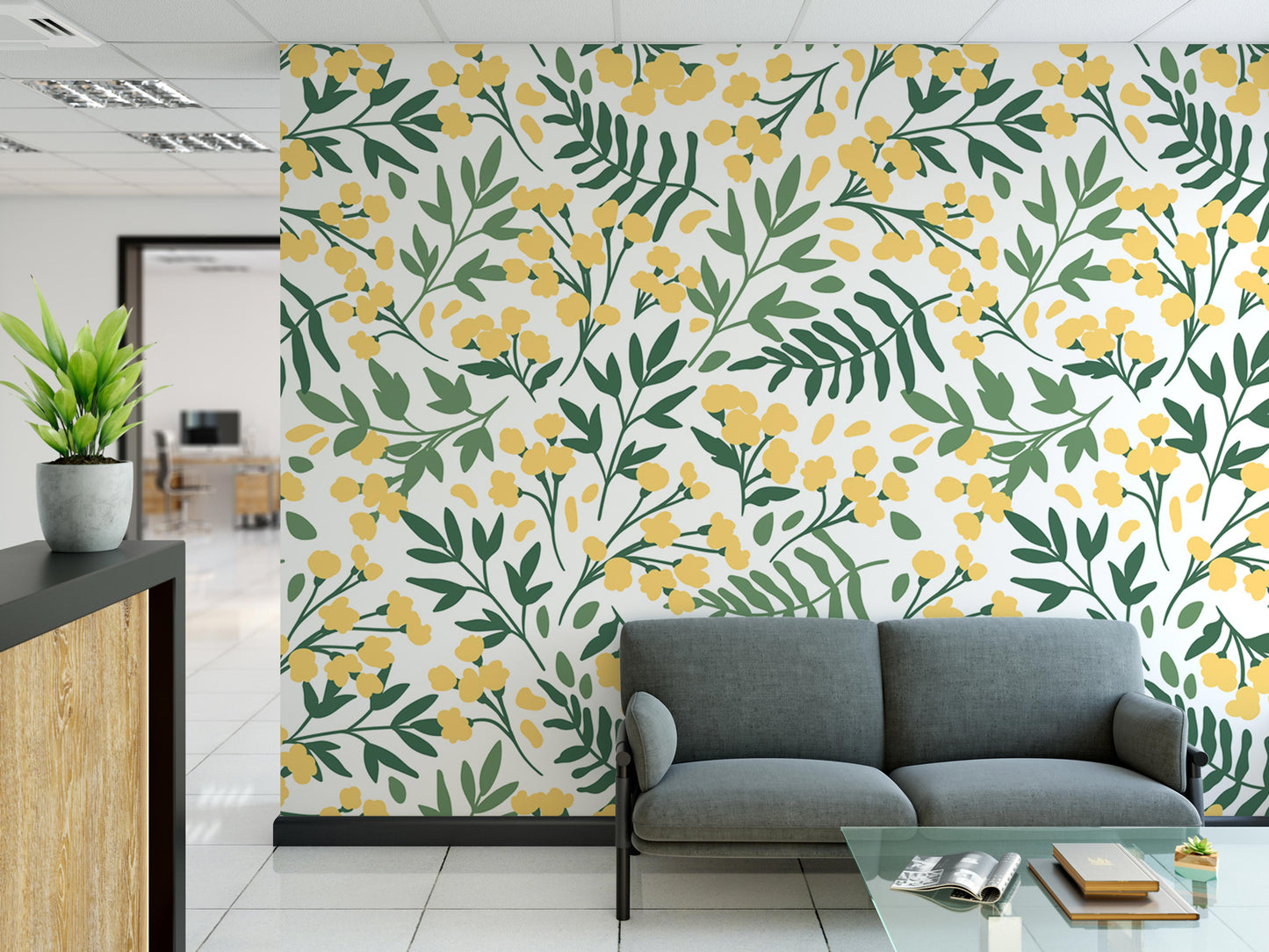 a modern living room with a gray sofa and a glass coffee table. The wall behind the sofa is decorated with a vibrant floral pattern in shades of yellow and green. The room also includes a potted plant and a bookshelf, creating a cozy and inviting atmosphere.