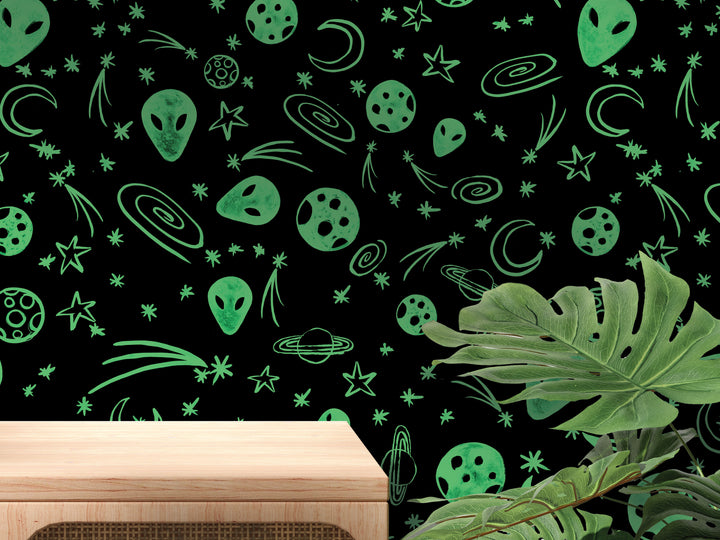 a wall with a black background adorned with various green and white celestial objects, such as planets, stars, and alien faces, creating a whimsical and imaginative space-themed design.