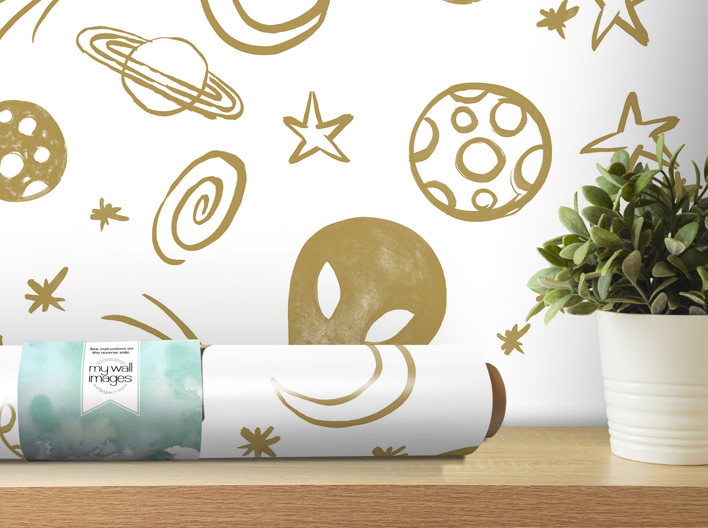 a wall with a wallpaper design of planets and stars, including a spiral galaxy, a crescent moon, and a smiling alien. There is also a potted plant on a shelf next to the wall.