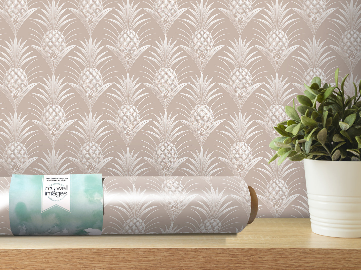 a roll of wallpaper with a repeating pattern of pineapples, placed on a wooden shelf next to a potted plant.