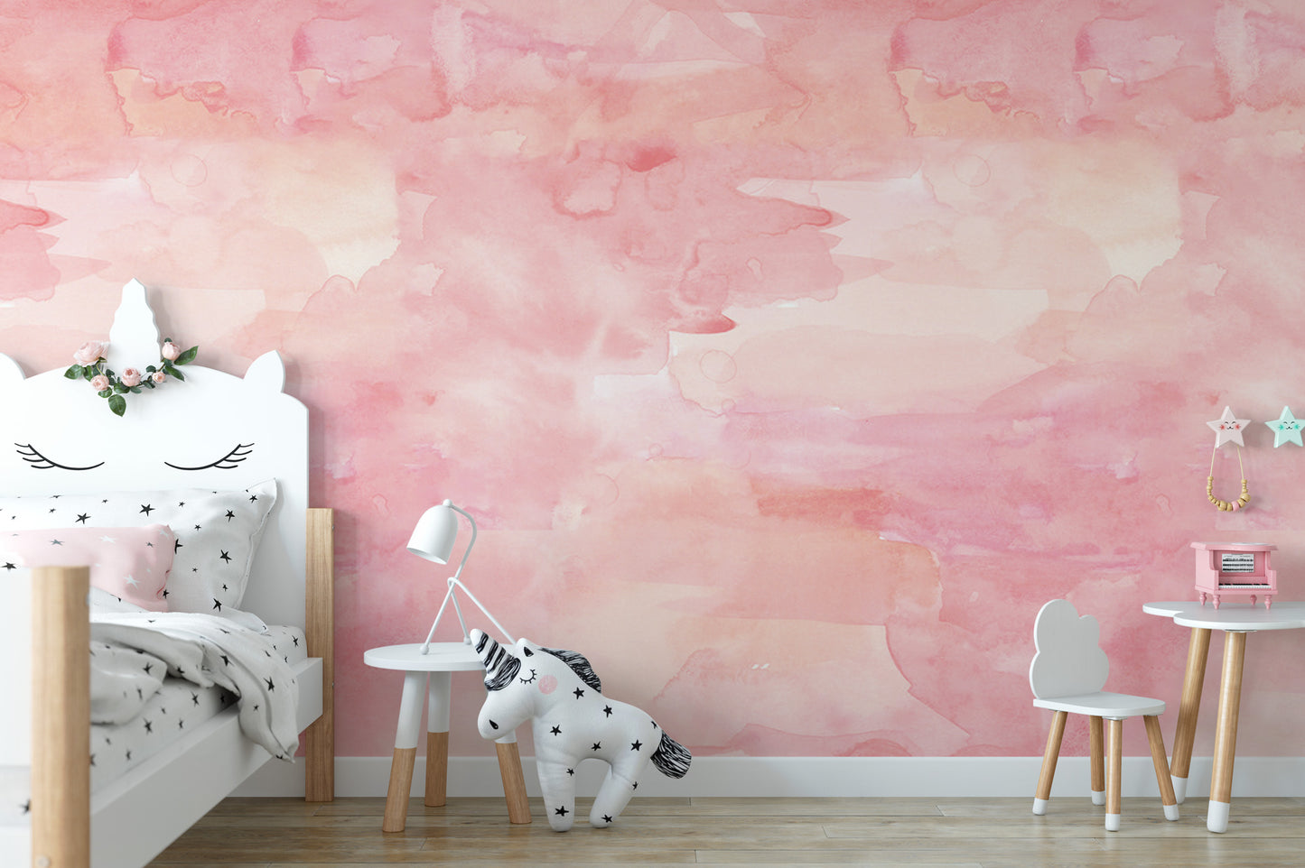 A child's bedroom with a pink and white color scheme, featuring a white bed with a unicorn headboard, a small table with a lamp, and a white chair.