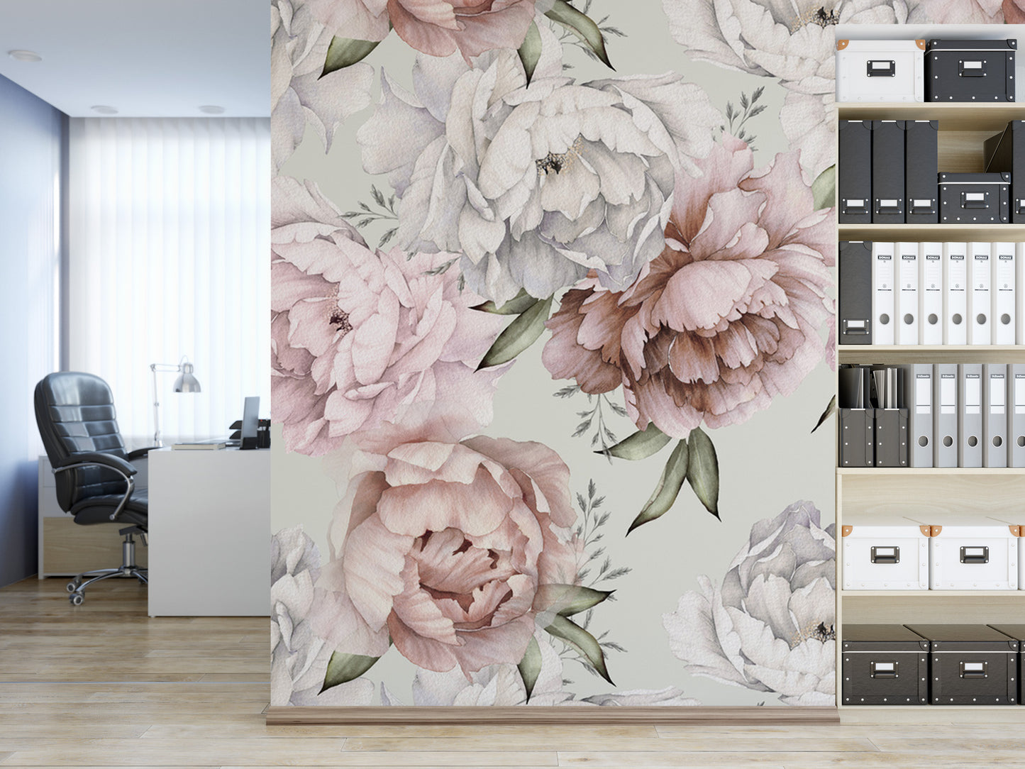 a wallpapered wall with a large floral design in shades of pink and white, including various types of flowers and leaves. The wall is adjacent to a bookshelf filled with books and binders, creating a cozy and organized workspace.
