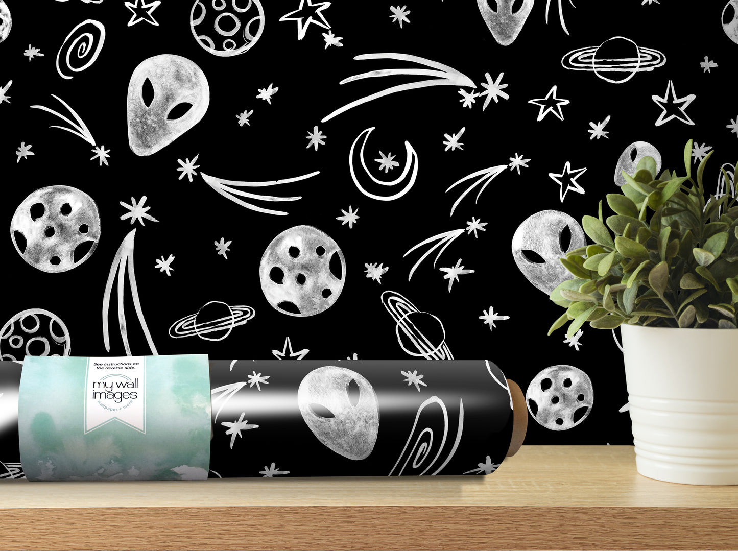 a black and white wallpaper with various celestial objects such as planets, stars, and comets, as well as a potted plant and a roll of wallpaper on a shelf.