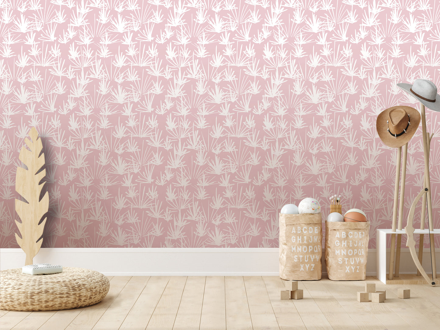 a pink wall with a repeating leaf pattern, a wicker basket, a wooden hat rack, and a stack of wooden blocks on a wooden floor.