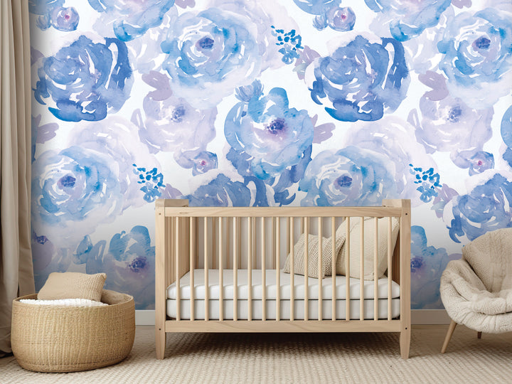a nursery room with a wooden crib, a beige chair, and a woven basket. The walls are decorated with a blue and white floral wallpaper.