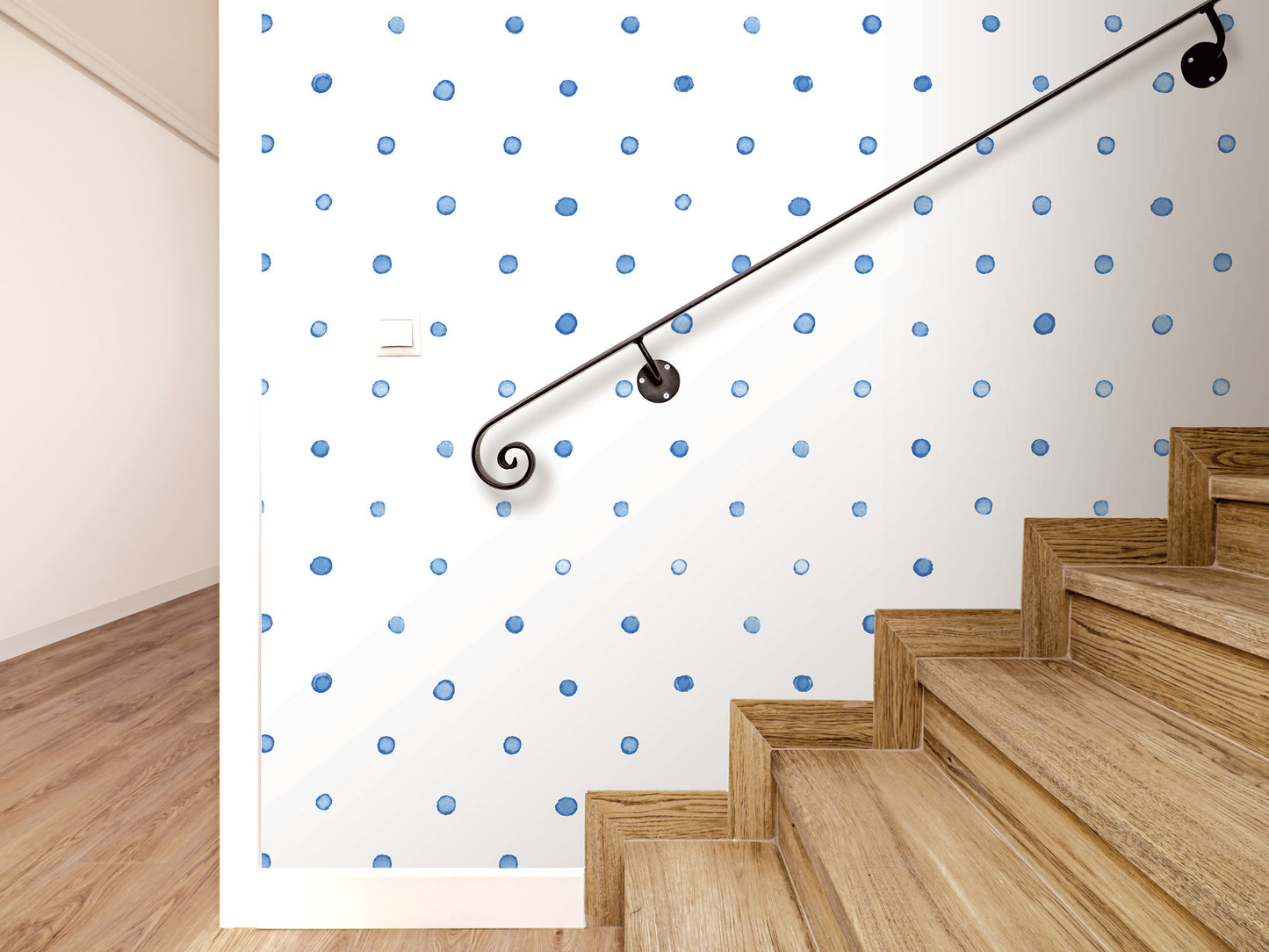 a staircase with a black metal handrail, and the wall behind it has a pattern of blue dots. The wooden steps of the staircase lead up to a white wall with a light switch.